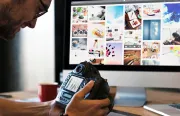 Man holding camera in front of computer screen