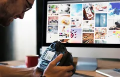 Man holding camera in front of computer screen